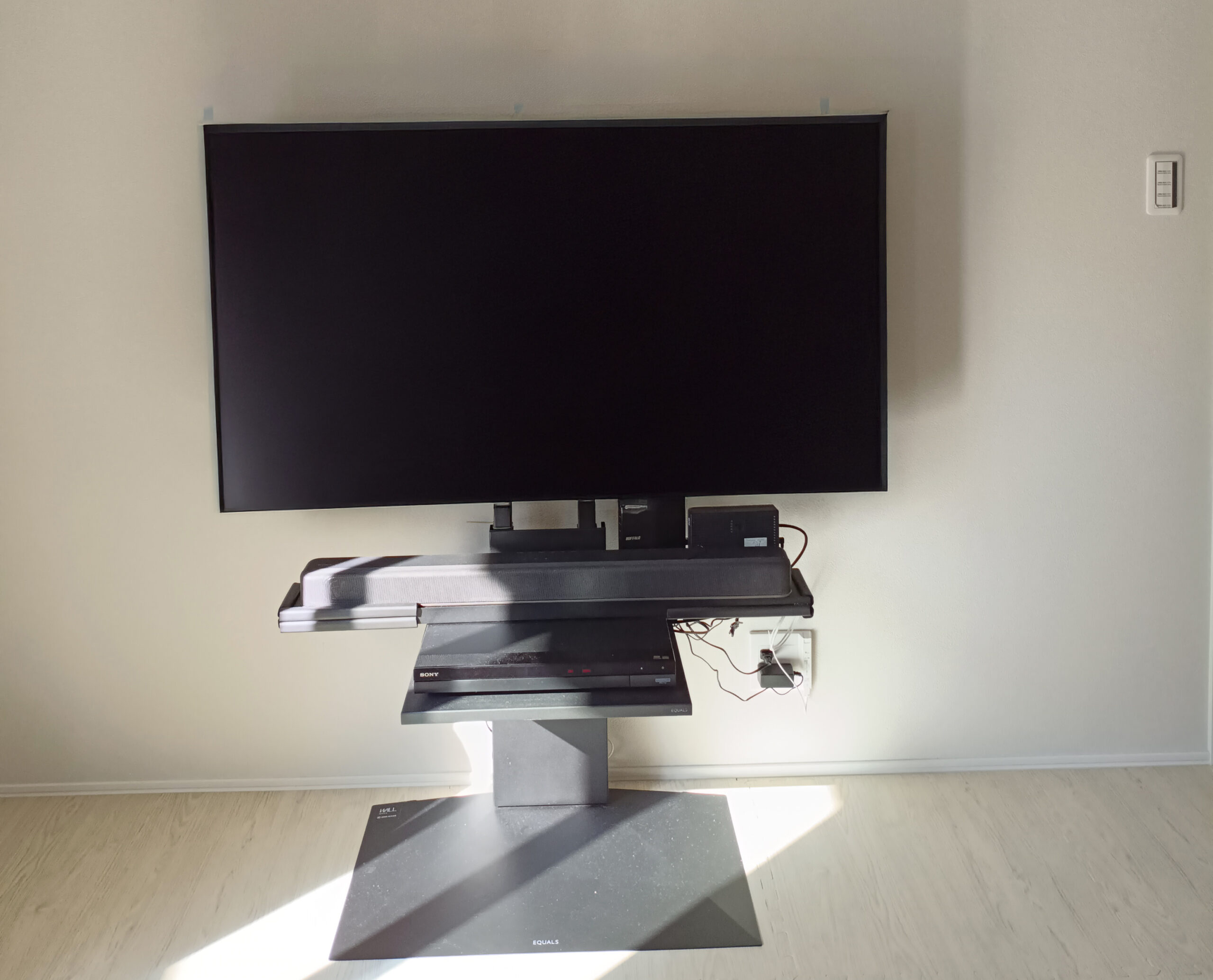 壁掛けテレビ施工前のリビング写真。テレビ台があり、配線が目立つ状態。